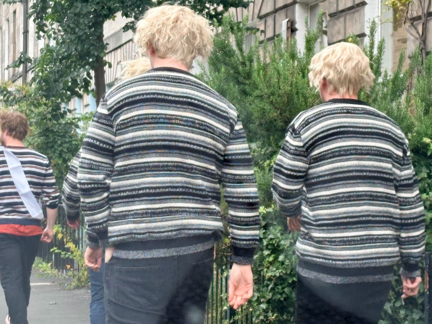Several young males in similar attire processing along Montagy St Edina as seen in a wing mirror and then finally passing the car