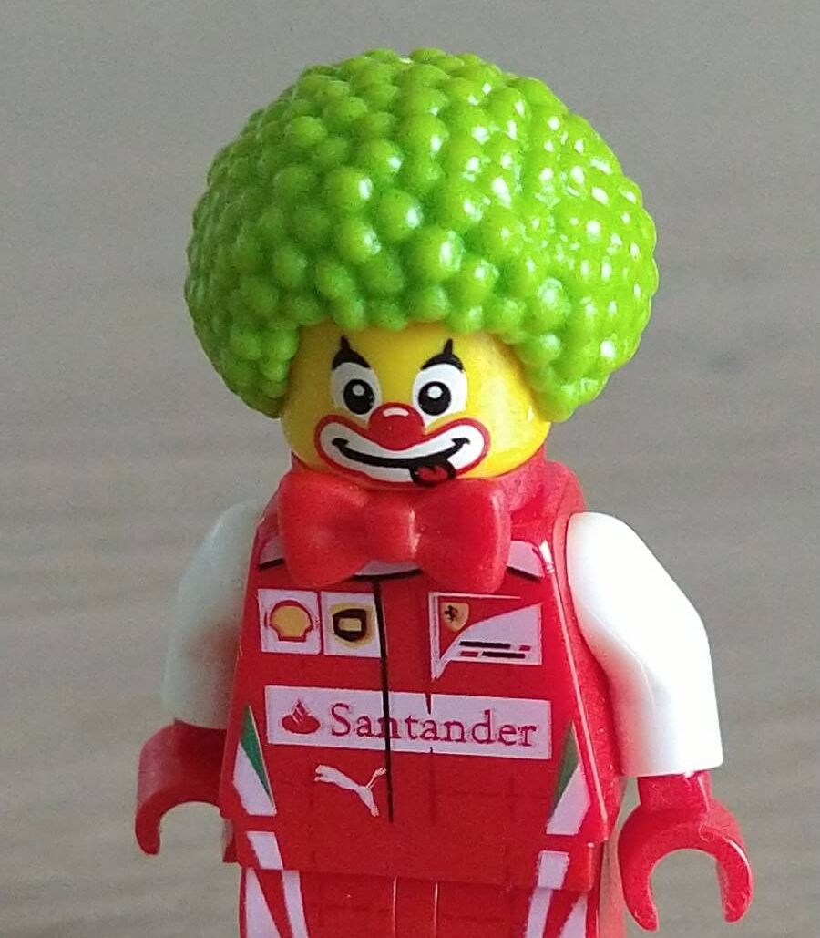 Lego minifigure in a Ferrari racing team overalls wearing a green clown hair piece and clown makeup