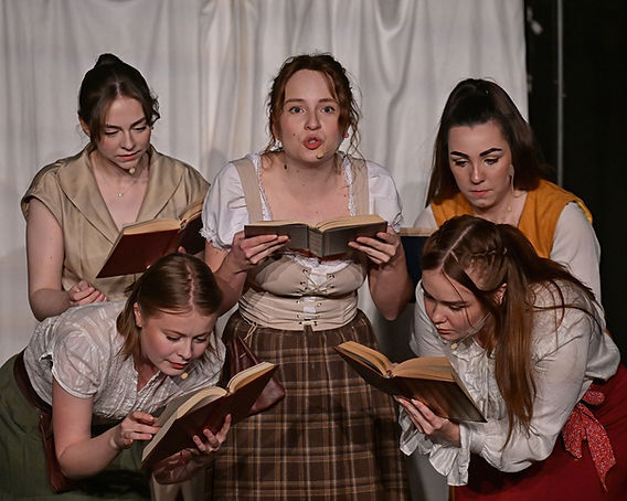 Group of five women arranged like the dots on a dice, engrossed in reading. Some in period dress.