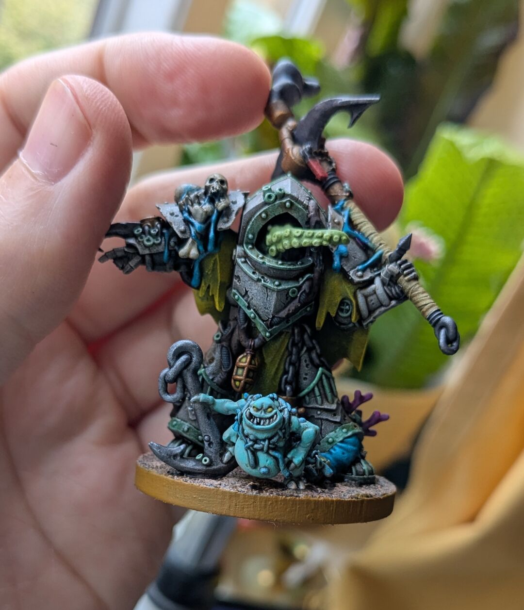 A close up of one of the miniatures showing off a "dredgeling" (Mezgike's version of a nurgling) that decorates the base of one of the minis. Said dredgeling is posing with an anchor and a fishing net cape. Its skin is an uncomfortable shade of turqoise.