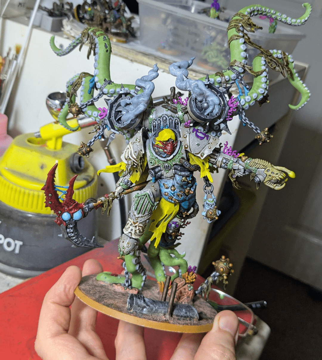 A large, painted wargaming miniature. A mutated figure who was clearly originally a power armoured super soldier but seems to have grown in scale at least 500%, sprouted many tentacles, and has some sort of tentacle-based jump pack. He also looks like he's lived under the sea for an extended period.